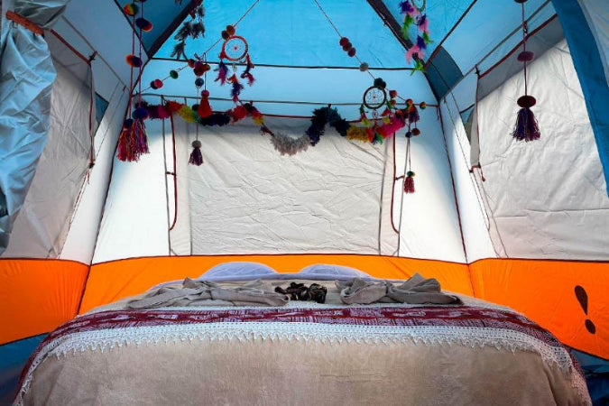 Inside a tent with colorful decorations and a bed.
