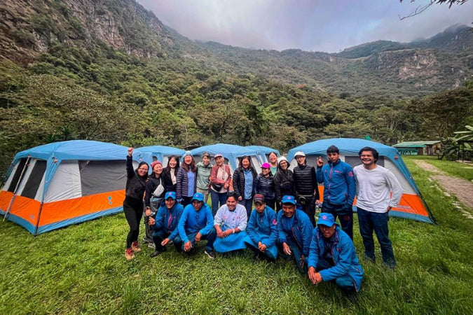 Group of people posing in front of camping tents in a mountainous area